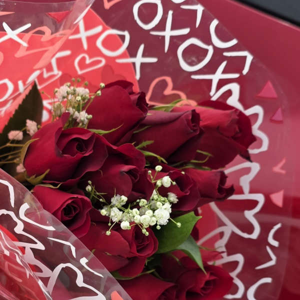 Bouquet of deep red roses with white baby's breath in pink wrap