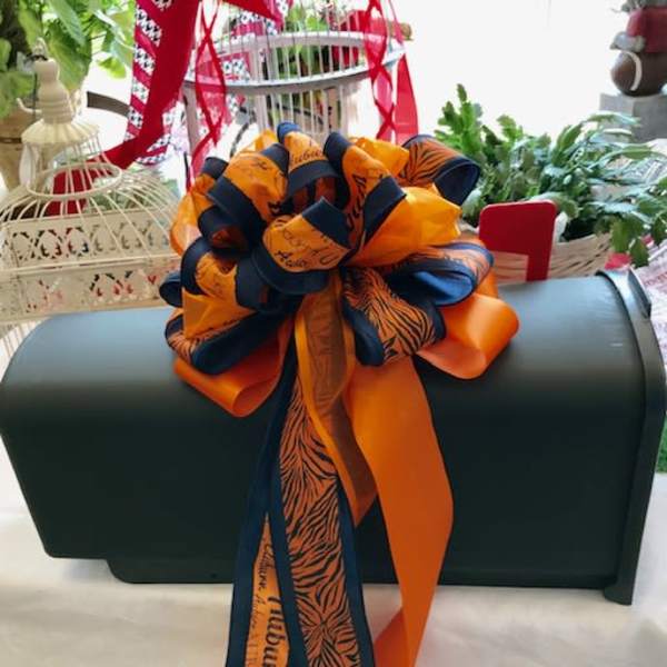 Dark green casket with a large orange and navy ribbon bow
