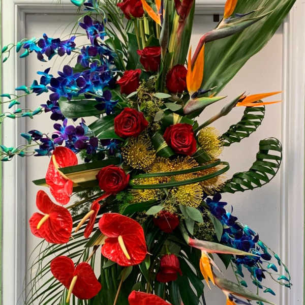 Tall tropical floral arrangement with red roses, blue orchids, and orange bird-of-paradise