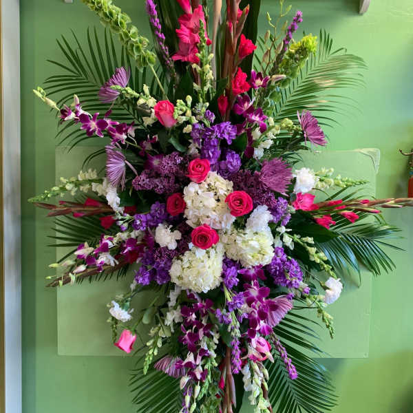 Tall floral spray with pink, purple, and white flowers on palm fronds