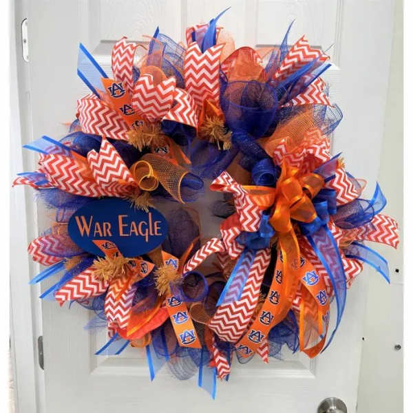 A blue and orange decorative wreath with Auburn War Eagle ribbons on a white door