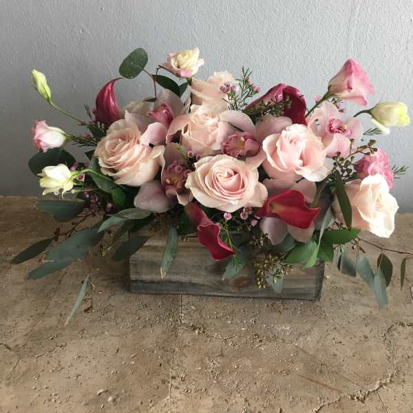 Pink roses and calla lilies arranged in a wooden box