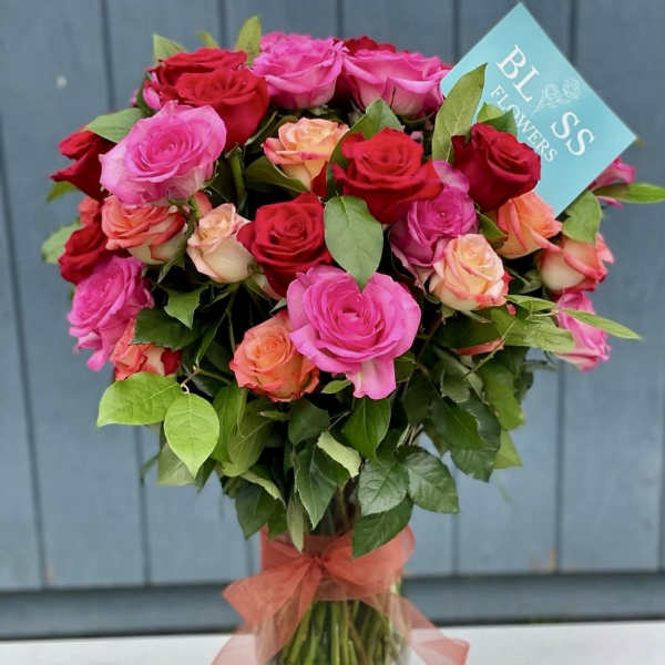 Bouquet of pink, red, and peach roses in a glass vase