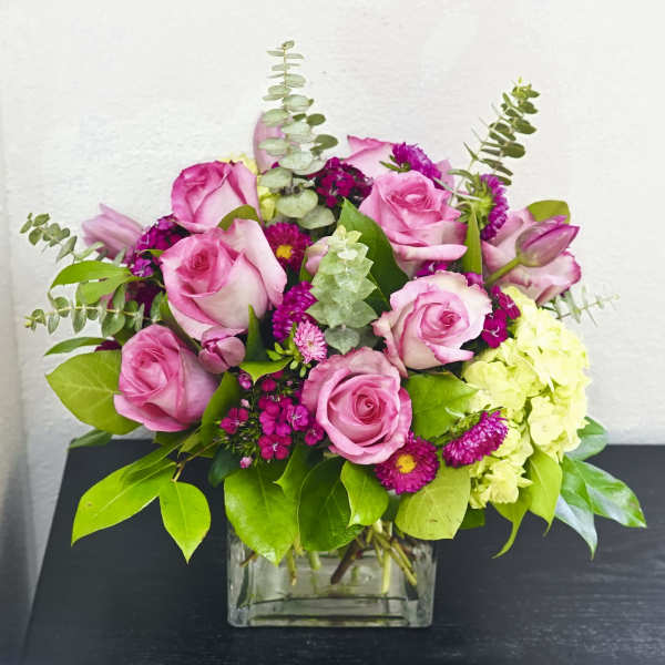 Pink roses and magenta flowers in a clear square vase