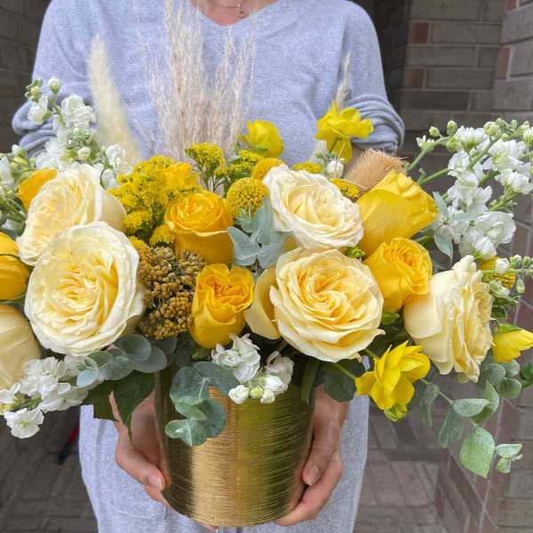 Yellow and white roses arranged in a gold vase