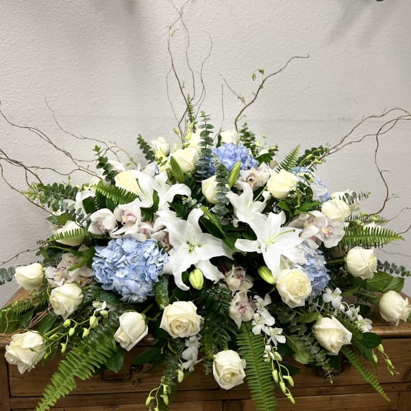 Large white floral arrangement with blue hydrangeas and roses