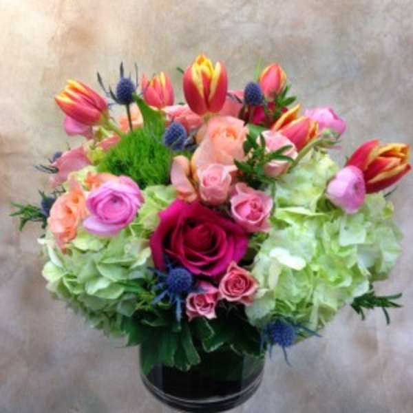 Mixed bouquet of roses, tulips, and hydrangeas in a glass vase
