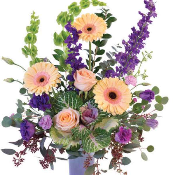 Mixed bouquet of peach and purple flowers in a lavender vase