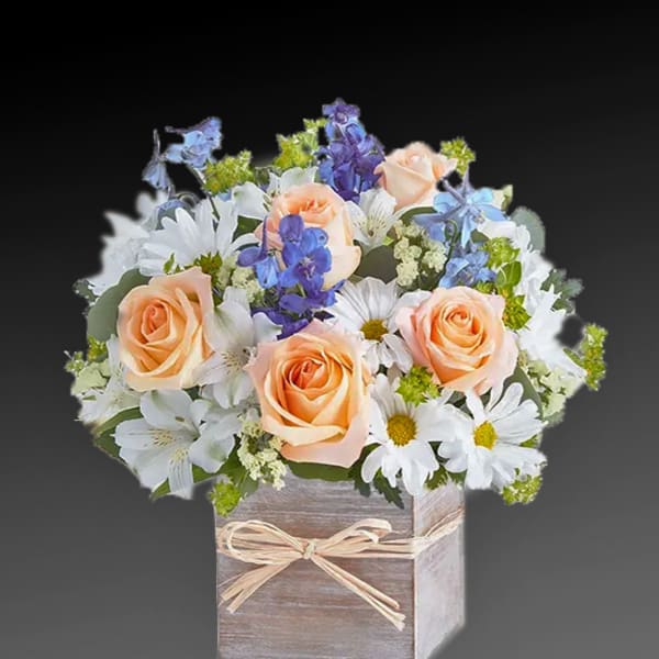 Peach roses and white daisies in a wooden box with a ribbon