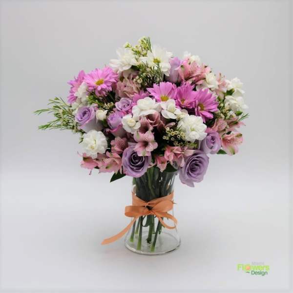 Bouquet of pink, white, and lavender flowers in a glass vase with an orange ribbon
