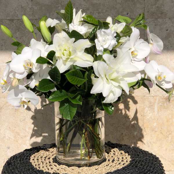 White orchids and lilies arranged in a clear glass vase