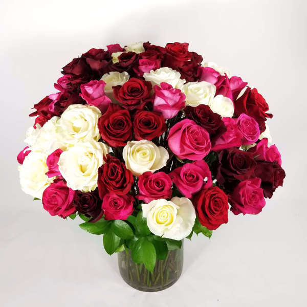 Large bouquet of red, pink, and white roses in a glass vase