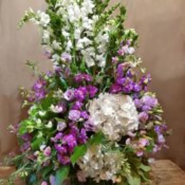 Tall arrangement of white and purple flowers with large white hydrangeas at the base