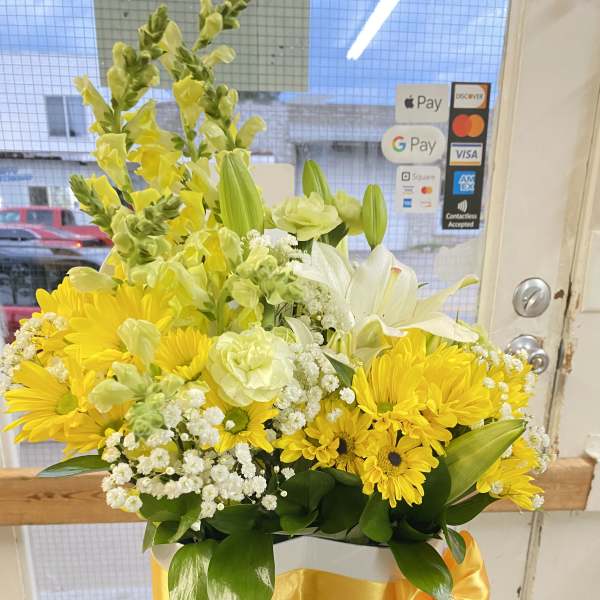 Yellow and white mixed flower arrangement in a white hatbox with a yellow ribbon bow