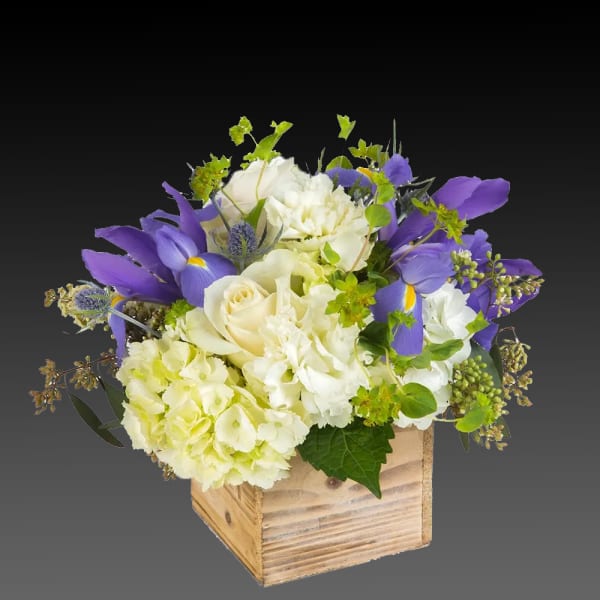 Purple and white floral arrangement in a wooden box