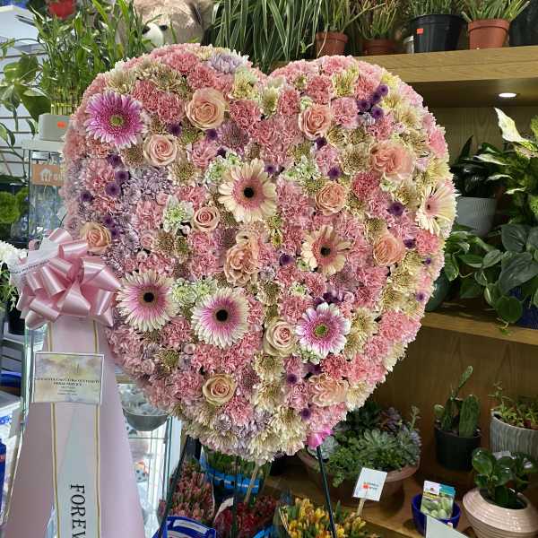 Heart-shaped pink floral standing spray with roses and gerbera daisies
