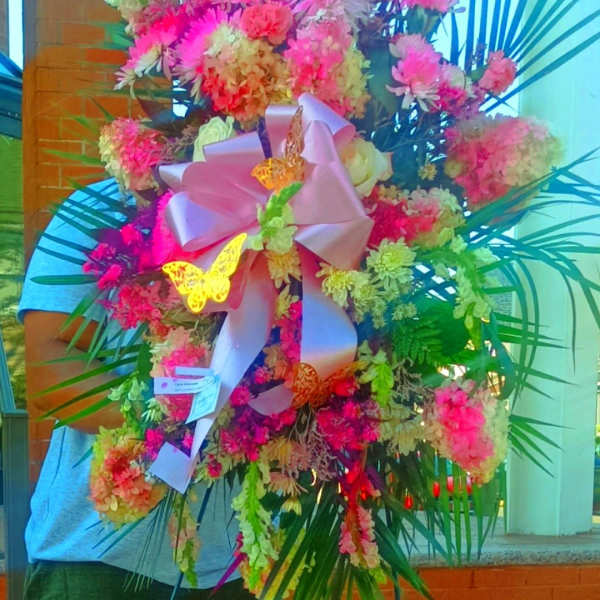 Large standing floral spray with pink and peach blooms on an easel