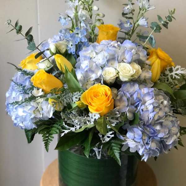 Bouquet of blue hydrangeas and yellow roses in a green vase