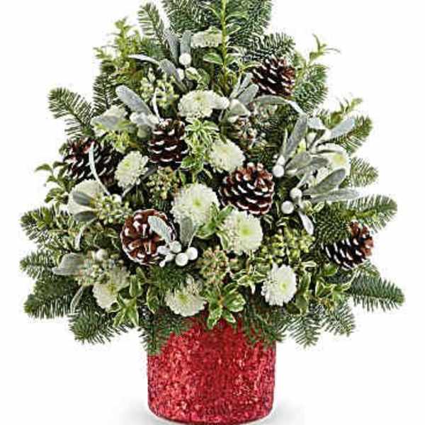 Christmas arrangement with white flowers, pinecones, and evergreen in a red container