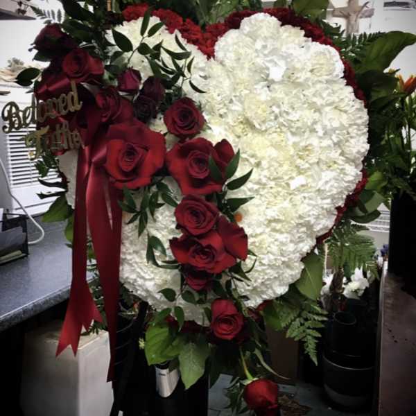 Heart-shaped floral tribute with white carnations and red roses