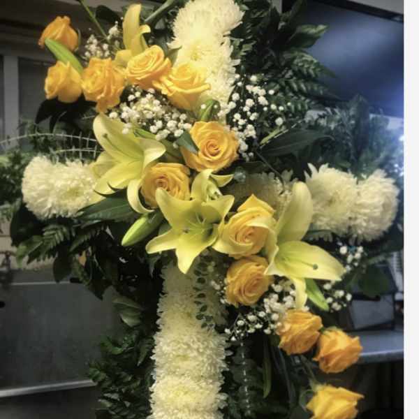 Yellow roses and lilies arranged in a white floral cross