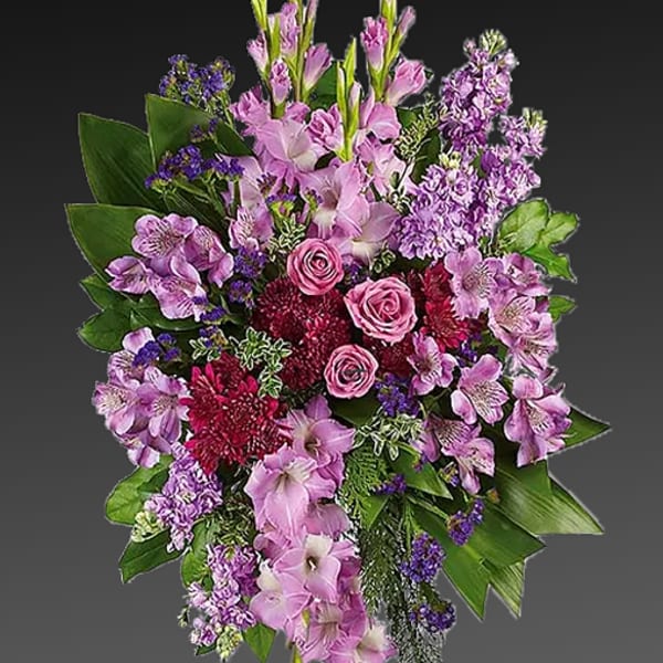 Standing floral spray with pink and purple flowers on a black easel