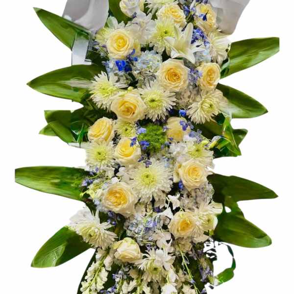 Tall floral standing spray with white and pale yellow blooms and a white bow
