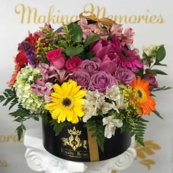 Mixed bouquet in a black round box with pink, purple, yellow, and orange flowers