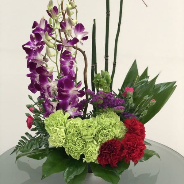 Purple orchids and red-green carnations in a low floral arrangement