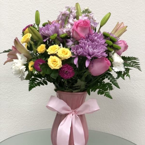 Pink and purple bouquet in a vase with a ribbon bow