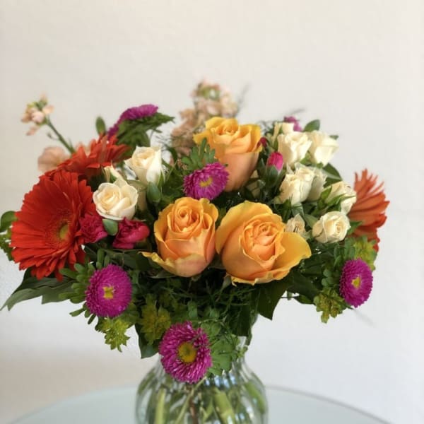 Mixed bouquet of roses and daisies in a clear glass vase