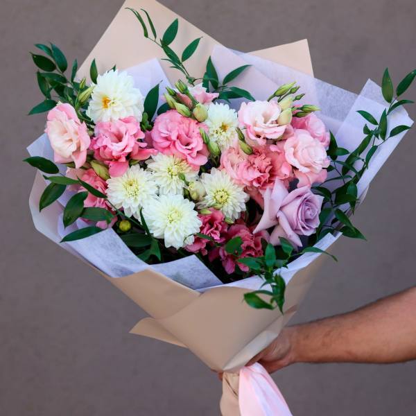 Hand-tied bouquet of pink and white flowers wrapped in beige paper