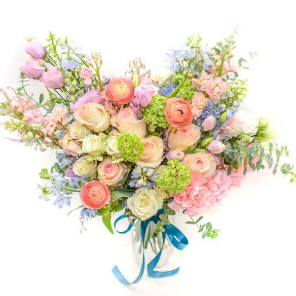 Pastel mixed flower bouquet with a blue ribbon in a clear vase