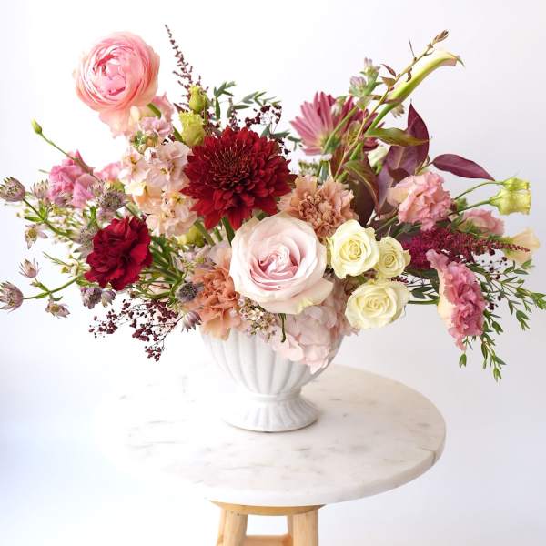 Mixed pink and red floral arrangement in a white vase