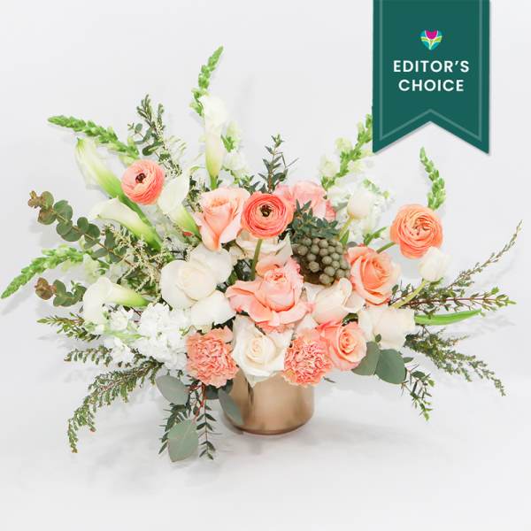 Peach and white floral arrangement in a gold vase