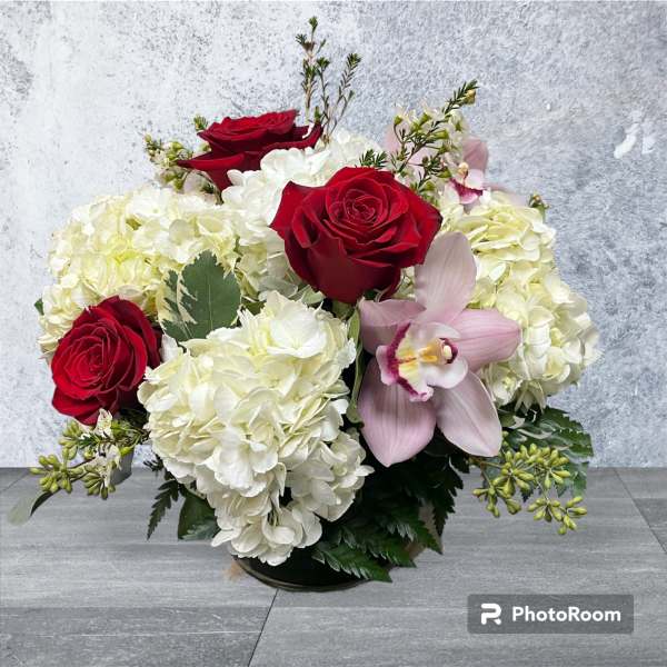 Bouquet of red roses, white hydrangeas, and a pink orchid in a low vase