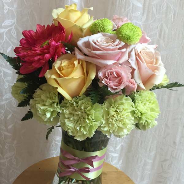 Mixed bouquet of roses, carnations, and daisies in a glass vase