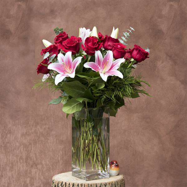 Bouquet of red roses and pink lilies in a clear glass vase