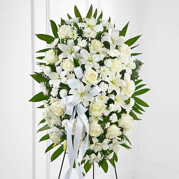 White floral standing spray with roses and lilies on an easel