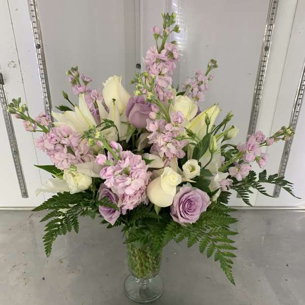 Pastel bouquet of roses, lilies, and pink stock in a glass vase