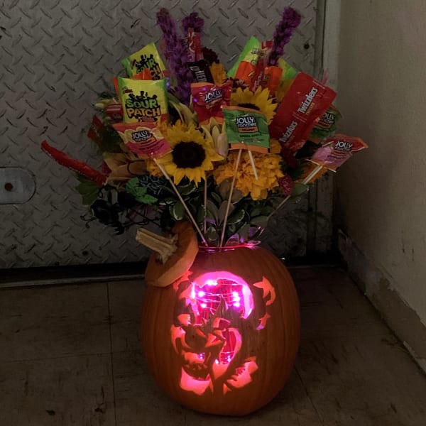 Carved pumpkin with candy bouquet and sunflowers