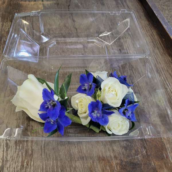 White roses and blue flowers in a clear plastic box