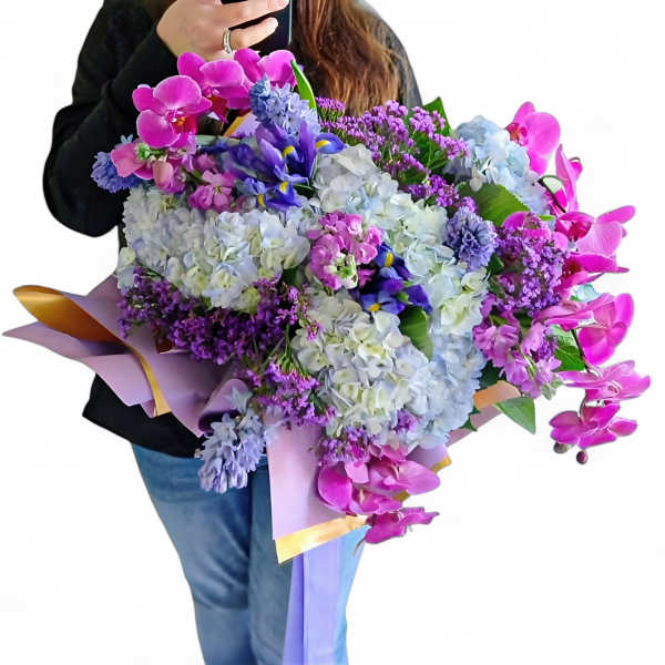 Large bouquet of pink, purple, and blue flowers wrapped in pastel paper