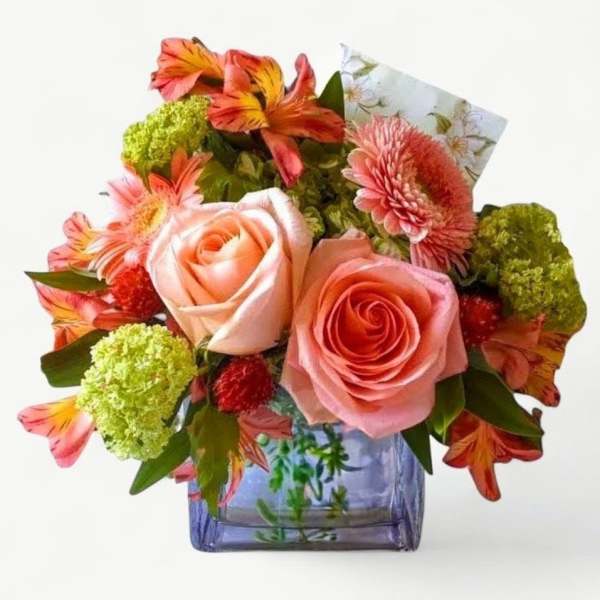 Peach roses, pink gerbera daisies, and orange alstroemeria in a purple glass cube vase.