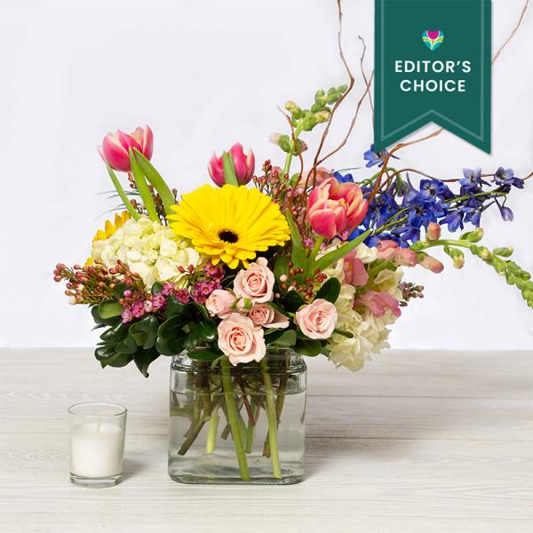 Mixed bouquet in a glass vase with a candle beside it