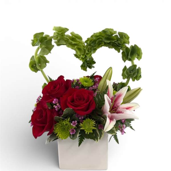 Red roses and white lilies in a white square vase with a green heart handle