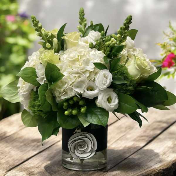 White floral arrangement in a glass vase with green foliage