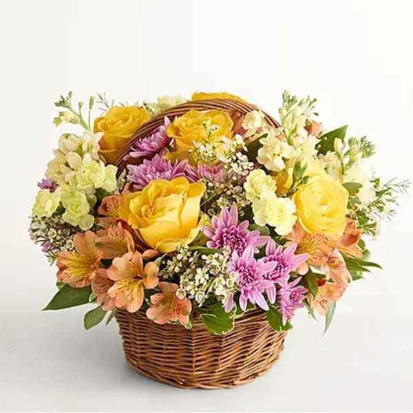 Basket of yellow roses and pink daisies with peach flowers