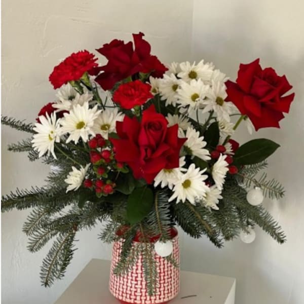 Red roses and white daisies in a red-and-white vase with evergreen branches