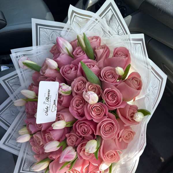 Bouquet of pink roses and tulip buds wrapped in clear paper